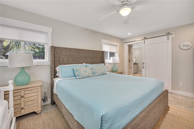 bedroom with a barn door, a ceiling fan, and baseboards