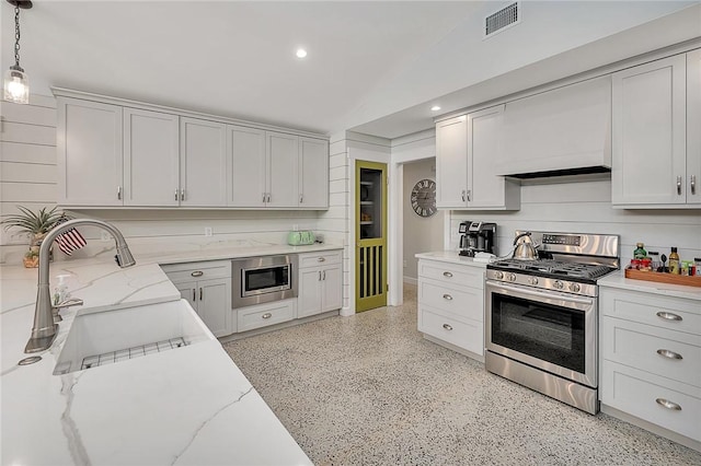 kitchen featuring visible vents, vaulted ceiling, appliances with stainless steel finishes, backsplash, and light stone countertops