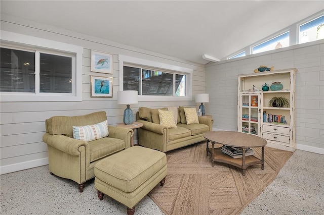 living area featuring lofted ceiling, speckled floor, and baseboards