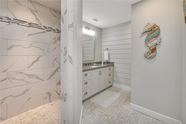 bathroom featuring wooden walls, visible vents, baseboards, walk in shower, and vanity