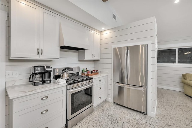 kitchen featuring light speckled floor, stainless steel appliances, visible vents, light stone countertops, and custom range hood