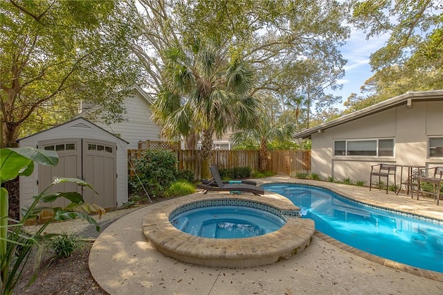 view of swimming pool with an outbuilding, a fenced backyard, a pool with connected hot tub, a storage unit, and a patio area