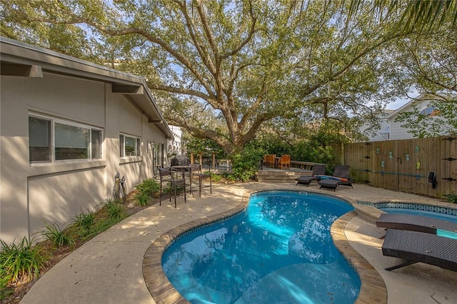 view of swimming pool with a wooden deck, a patio area, fence, and a fenced in pool