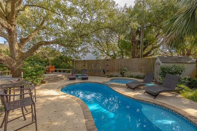 view of swimming pool featuring a patio area, fence, a storage unit, and an outbuilding