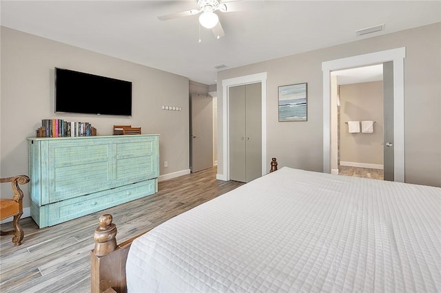 bedroom featuring visible vents, baseboards, a ceiling fan, wood finished floors, and ensuite bathroom