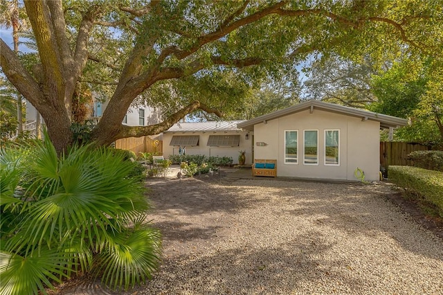 rear view of house featuring fence and stucco siding