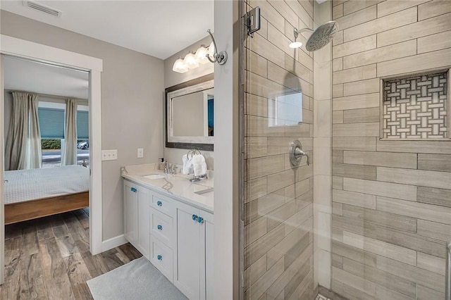 full bathroom featuring connected bathroom, visible vents, tiled shower, and wood finished floors