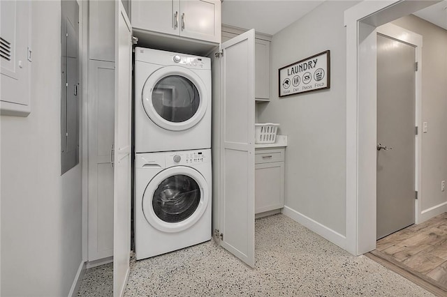 laundry area featuring laundry area, stacked washing maching and dryer, and baseboards