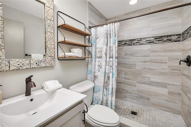 full bathroom with a tile shower, vanity, and toilet