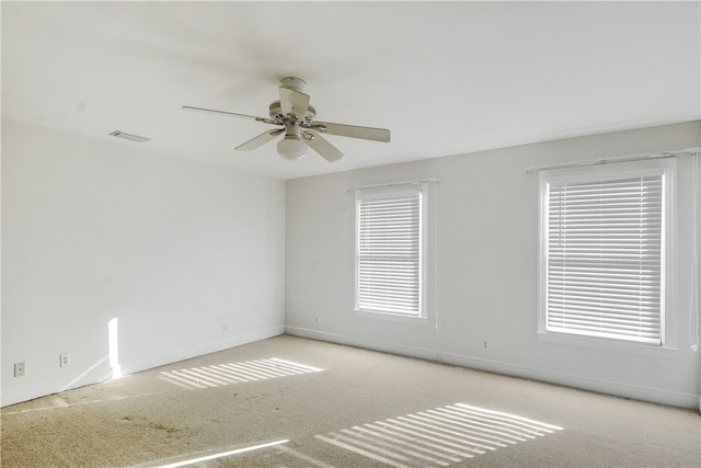 carpeted empty room featuring ceiling fan and a healthy amount of sunlight