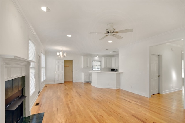 unfurnished living room featuring a tile fireplace, ceiling fan with notable chandelier, light hardwood / wood-style floors, and ornamental molding