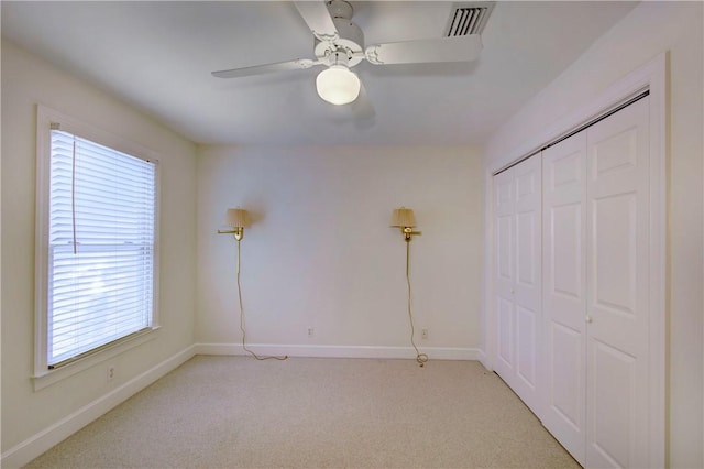 unfurnished bedroom featuring ceiling fan, light colored carpet, and a closet