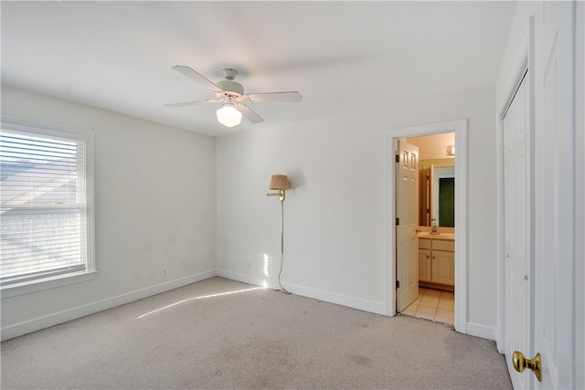 unfurnished bedroom with ensuite bathroom, light colored carpet, ceiling fan, sink, and a closet