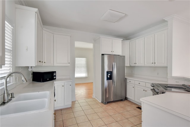 kitchen with light tile patterned flooring, sink, white cabinetry, and stainless steel appliances