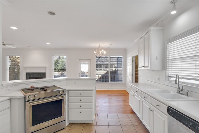 kitchen with white cabinets, ceiling fan with notable chandelier, sink, light wood-type flooring, and stainless steel appliances