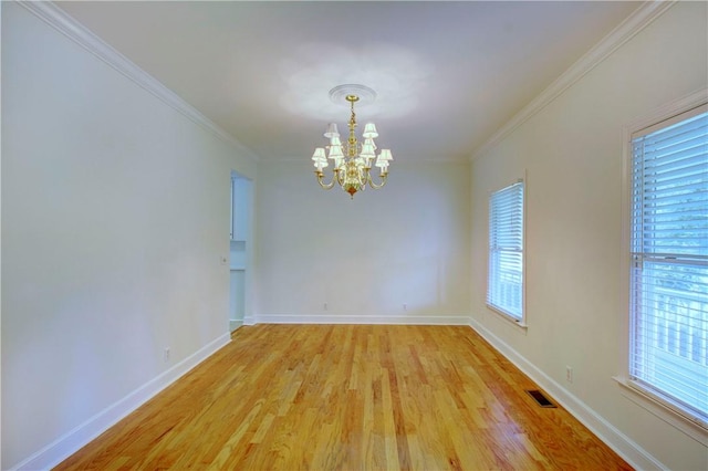 empty room with wood-type flooring, crown molding, plenty of natural light, and a notable chandelier