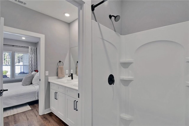 ensuite bathroom with ensuite bathroom, wood finished floors, recessed lighting, a shower, and vanity