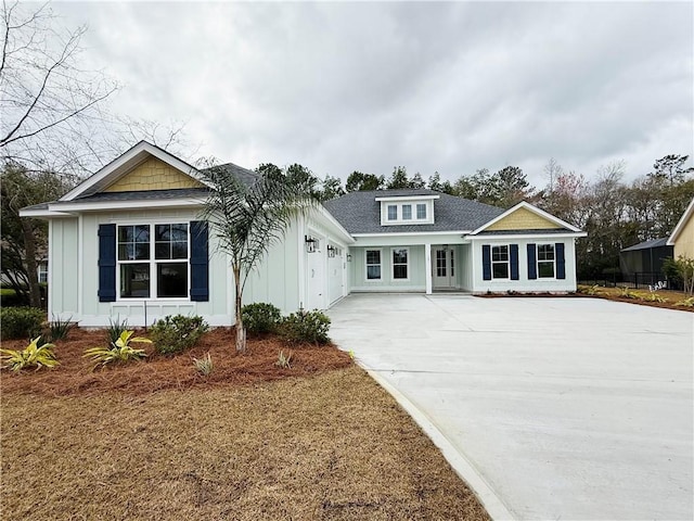 view of front of house with an attached garage, board and batten siding, driveway, and a shingled roof