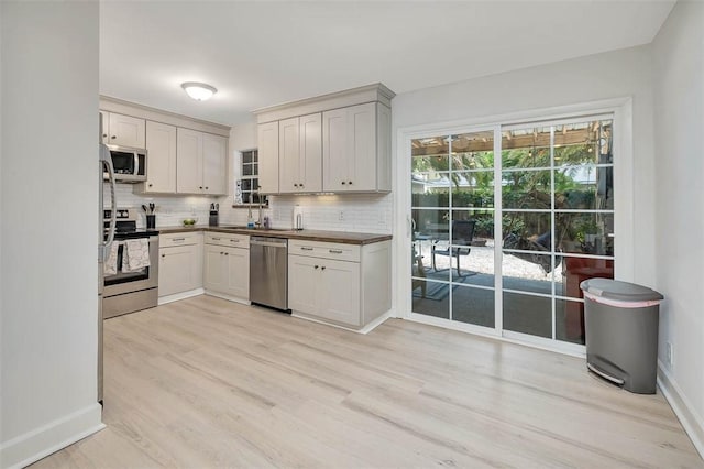 205 Palmetto St, Saint Simons Island, GA 31522 - kitchen featuring stainless steel appliances, decorative backsplash, light wood finished floors, and dark countertops