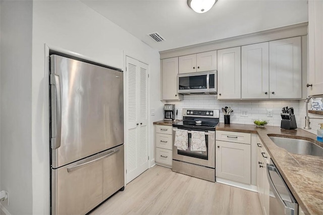 205 Palmetto St, Saint Simons Island, GA 31522 - kitchen featuring stainless steel appliances, light wood-style flooring, and tasteful backsplash