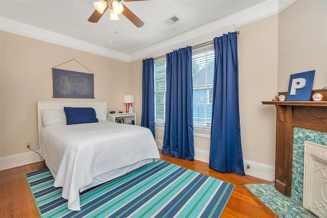 bedroom with visible vents, ornamental molding, wood finished floors, baseboards, and ceiling fan