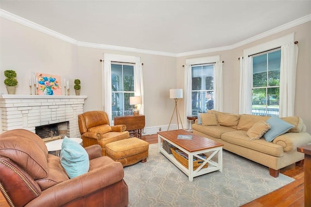 living room featuring baseboards, a brick fireplace, wood finished floors, and crown molding