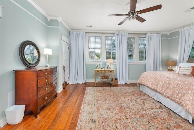 bedroom with visible vents, crown molding, ceiling fan, baseboards, and wood finished floors