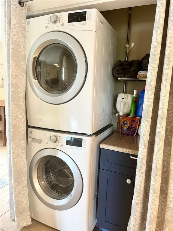 washroom with light tile patterned flooring and stacked washer / drying machine