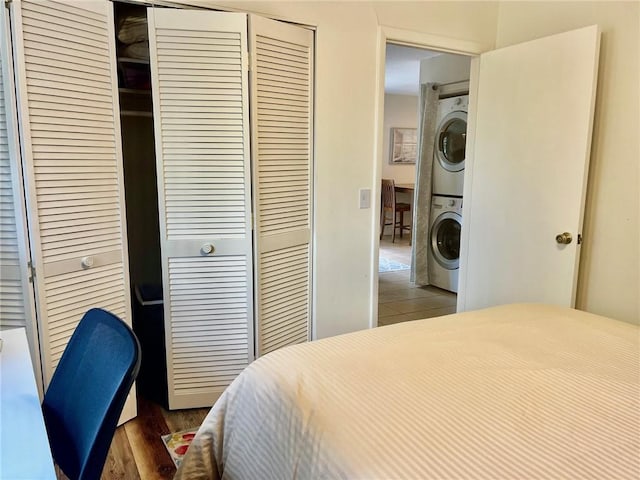 bedroom with dark hardwood / wood-style flooring and stacked washer and dryer