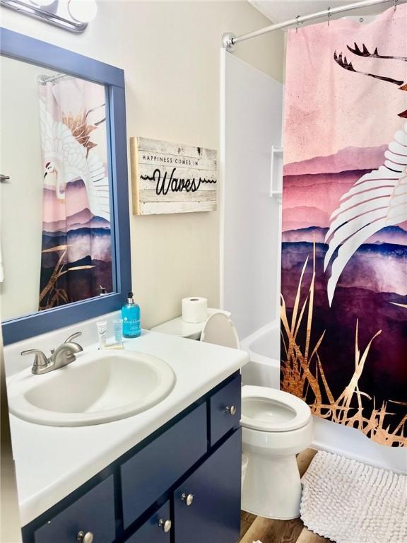 full bathroom with wood-type flooring, vanity, toilet, and shower / bathtub combination with curtain