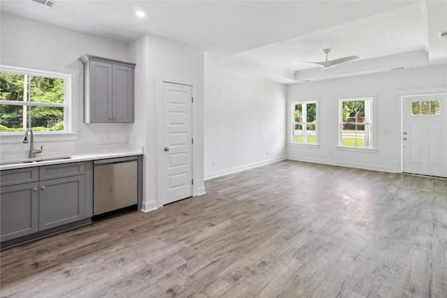 kitchen with stainless steel dishwasher, gray cabinetry, ceiling fan, sink, and light hardwood / wood-style flooring