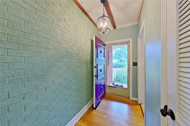 doorway to outside featuring light wood-style floors, brick wall, and crown molding