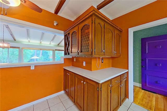 kitchen with beam ceiling, baseboards, brown cabinetry, and light tile patterned floors