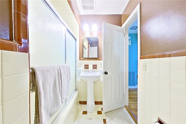 bathroom with tile walls and a shower with shower door