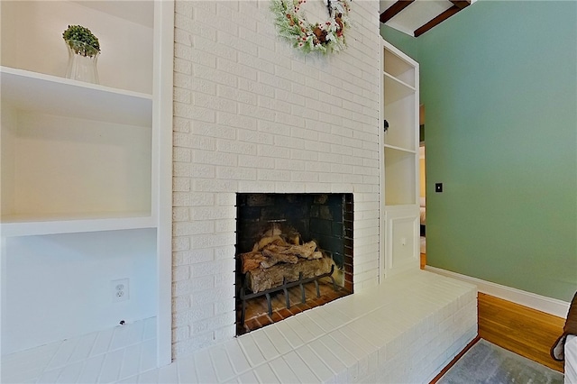 detailed view of a brick fireplace, wood finished floors, and baseboards