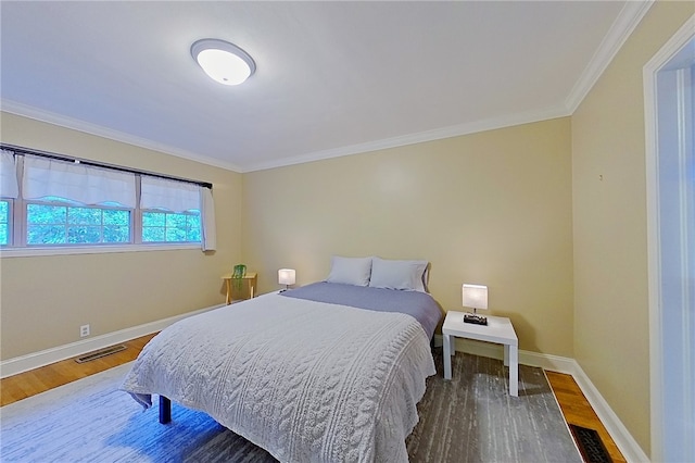 bedroom with wood finished floors, ornamental molding, and baseboards