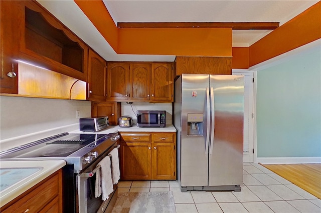 kitchen with stainless steel appliances, open shelves, brown cabinets, and light countertops
