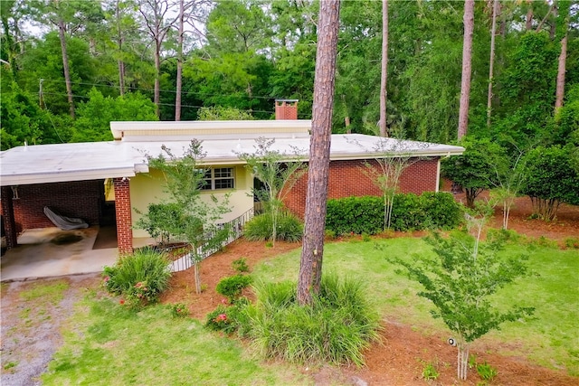 view of front of home with a carport, a chimney, and brick siding
