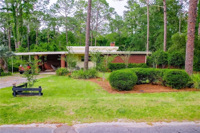 back of property with a chimney, an attached carport, and a lawn