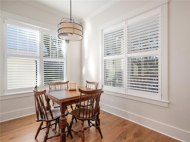 dining space featuring wood-type flooring, a wealth of natural light, and crown molding