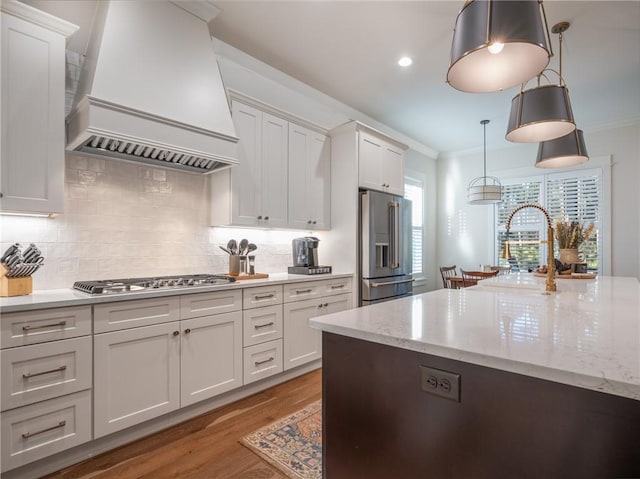 kitchen featuring backsplash, premium range hood, white cabinetry, hanging light fixtures, and appliances with stainless steel finishes