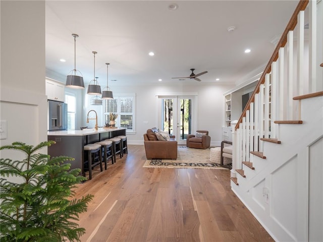 living room featuring ceiling fan, a wealth of natural light, ornamental molding, and hardwood / wood-style flooring