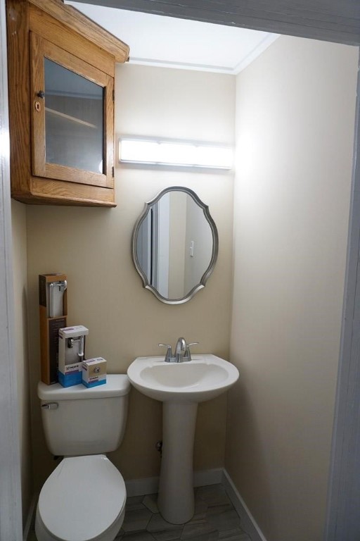 bathroom featuring toilet, tile patterned floors, ornamental molding, and sink