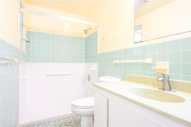 bathroom featuring vanity, toilet, tile walls, and a tile shower