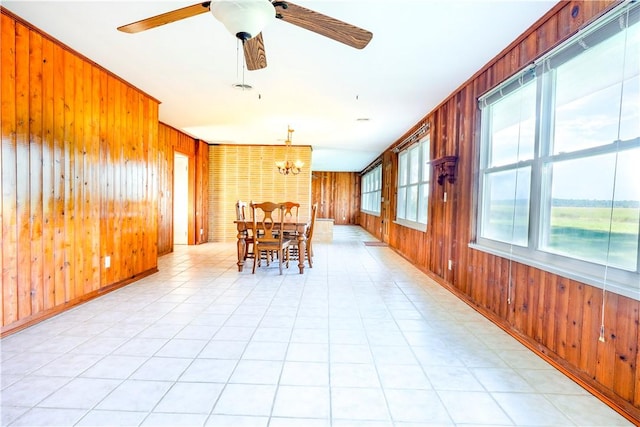 unfurnished dining area with ceiling fan with notable chandelier and wooden walls