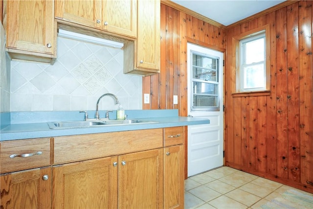 kitchen featuring backsplash, wood walls, sink, and light tile patterned flooring