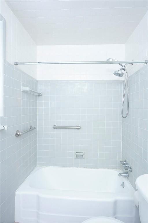 bathroom featuring tiled shower / bath combo and toilet