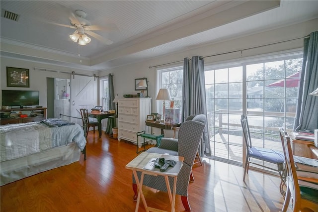 12 Wimbledon Ct, Saint Simons Island, GA 31522 - bedroom featuring a raised ceiling, ornamental molding, a barn door, wood finished floors, and access to outside