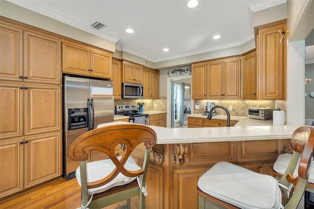257 Villager Dr, Saint Simons Island, GA 31522 - kitchen featuring appliances with stainless steel finishes, a sink, a peninsula, light countertops, and decorative backsplash