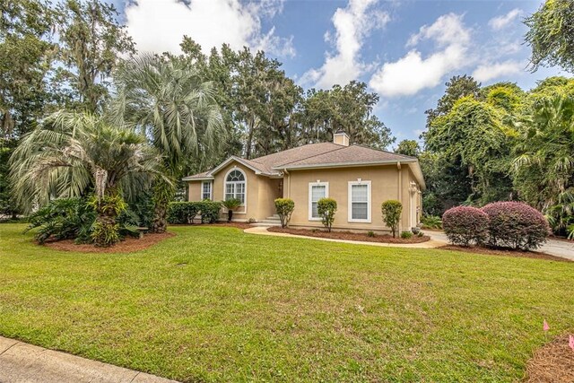 1064 Sea Palms W Dr, Saint Simons Island, GA 31522 - view of front facade featuring stucco siding, a front yard, and a chimney